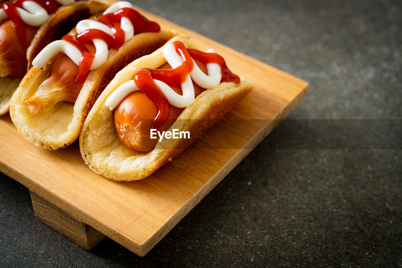 HIGH ANGLE VIEW OF HOT DOG AND CUTTING BOARD