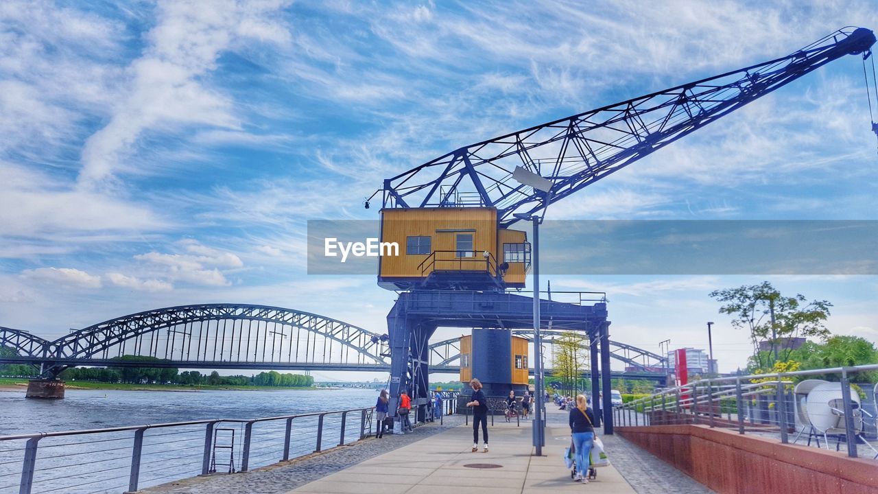 PEOPLE AT BRIDGE IN CITY AGAINST SKY