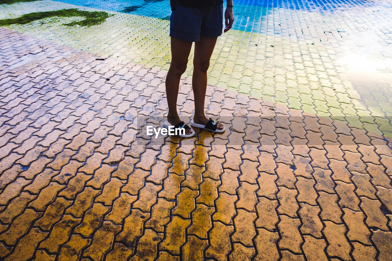 LOW SECTION OF WOMAN STANDING ON ZEBRA CROSSING