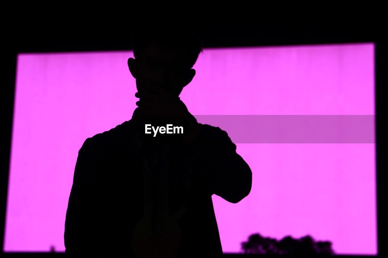Silhouette man standing against purple wall