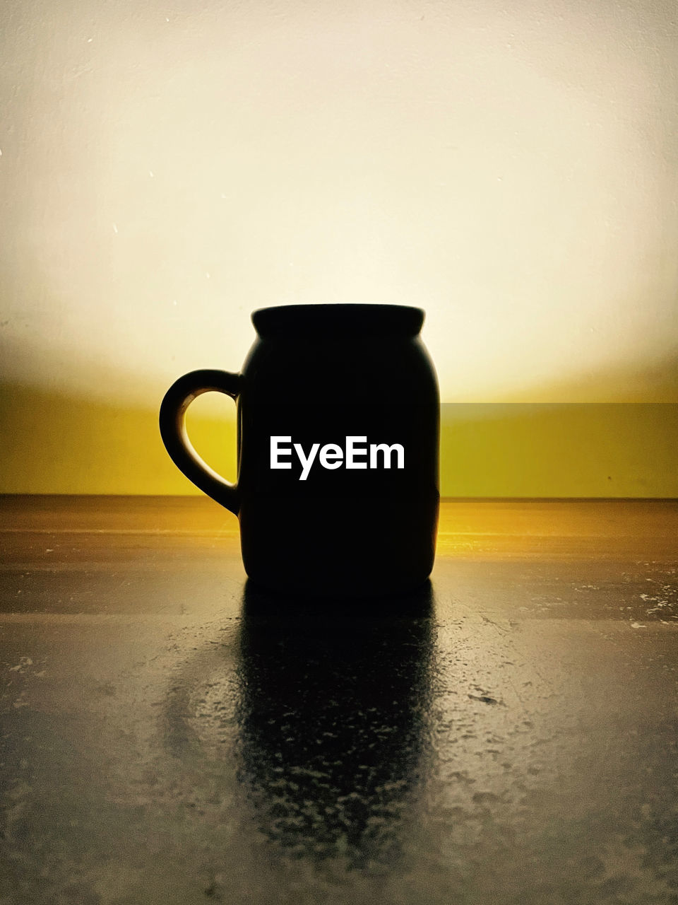 CLOSE-UP OF COFFEE CUP ON TABLE AGAINST SUNSET SKY
