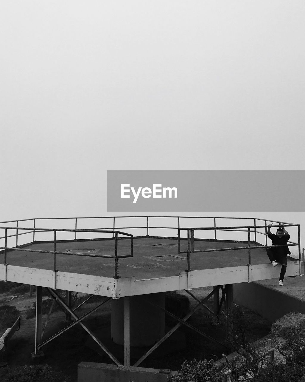 Man standing on footbridge over sea against clear sky
