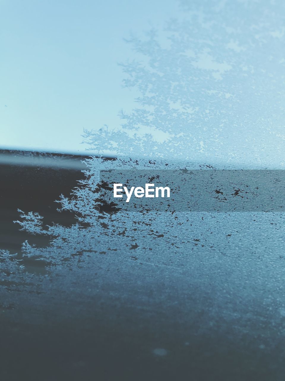 CLOSE-UP OF FROZEN LAKE AGAINST SKY