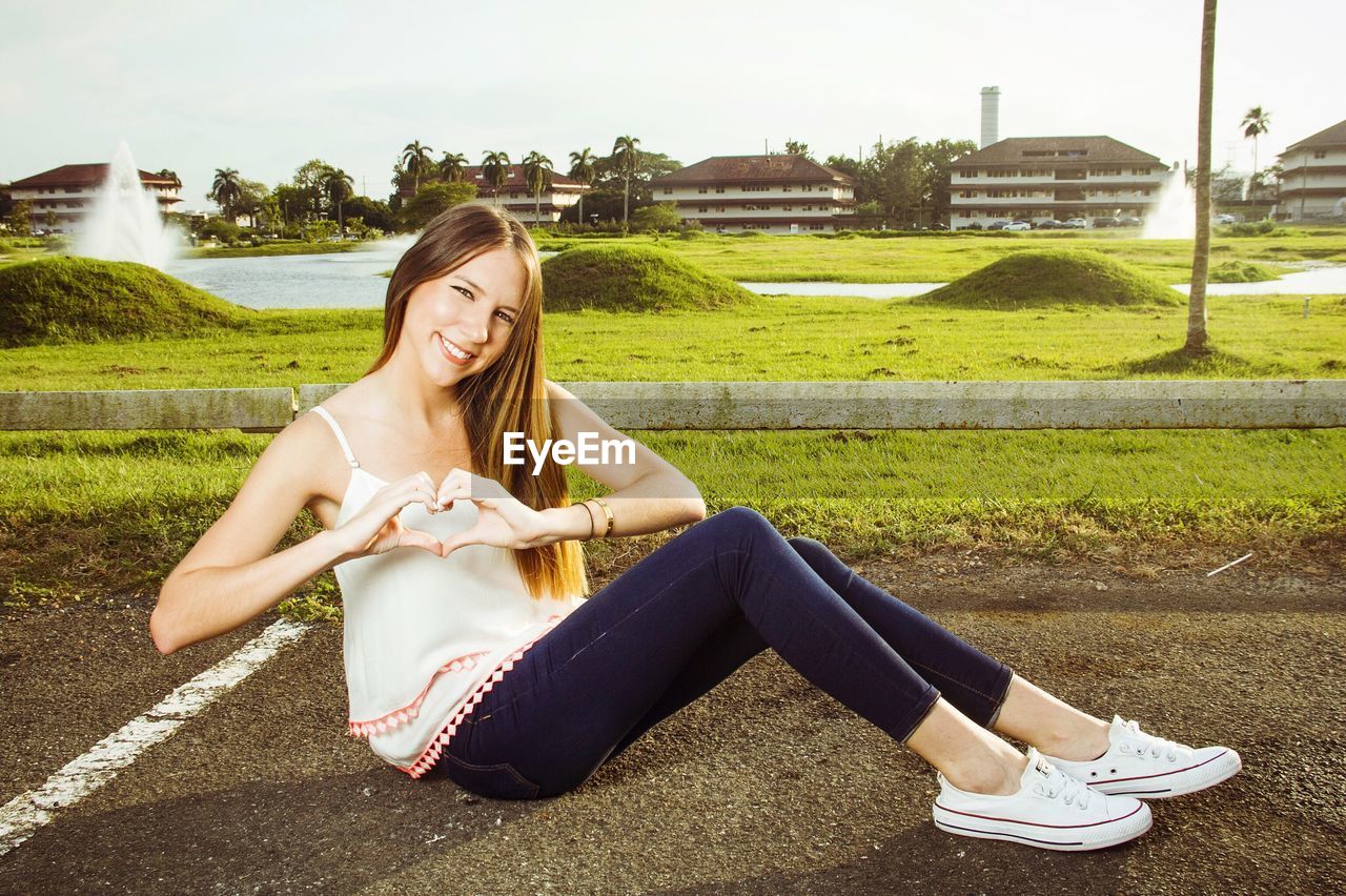 REAR VIEW OF WOMAN SITTING ON LAWN