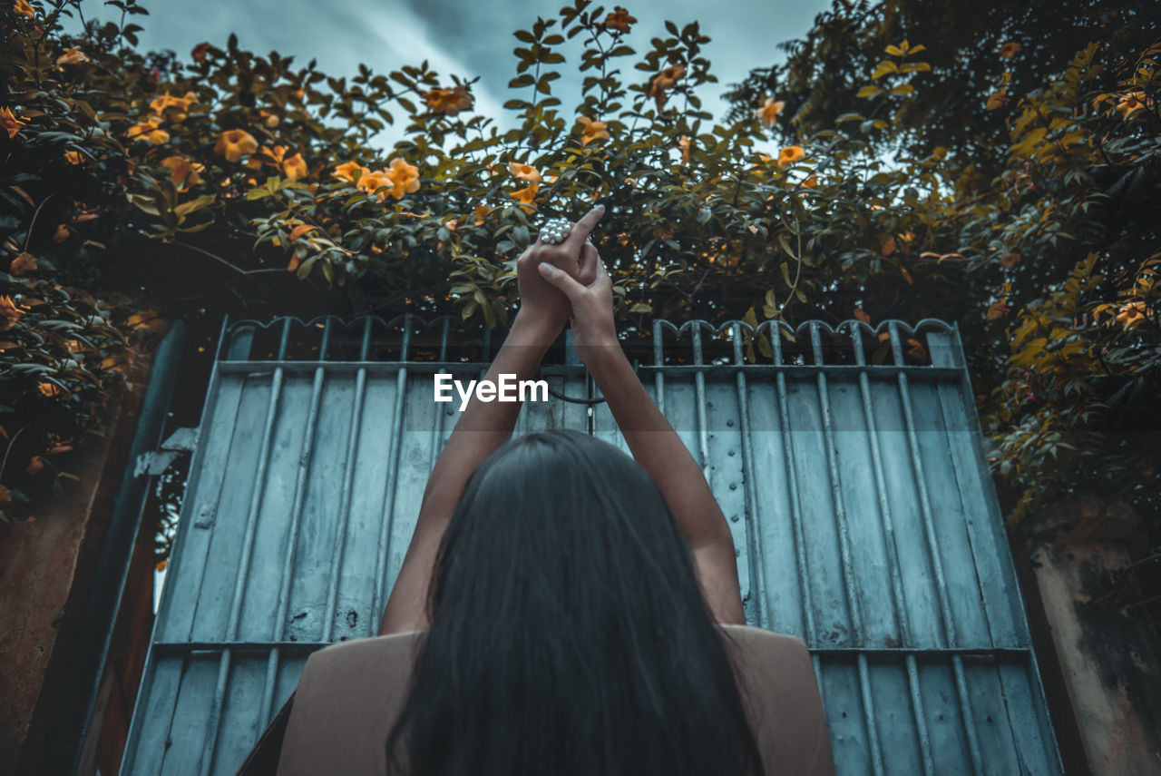 Rear view of woman relaxing while sitting on chair against gate