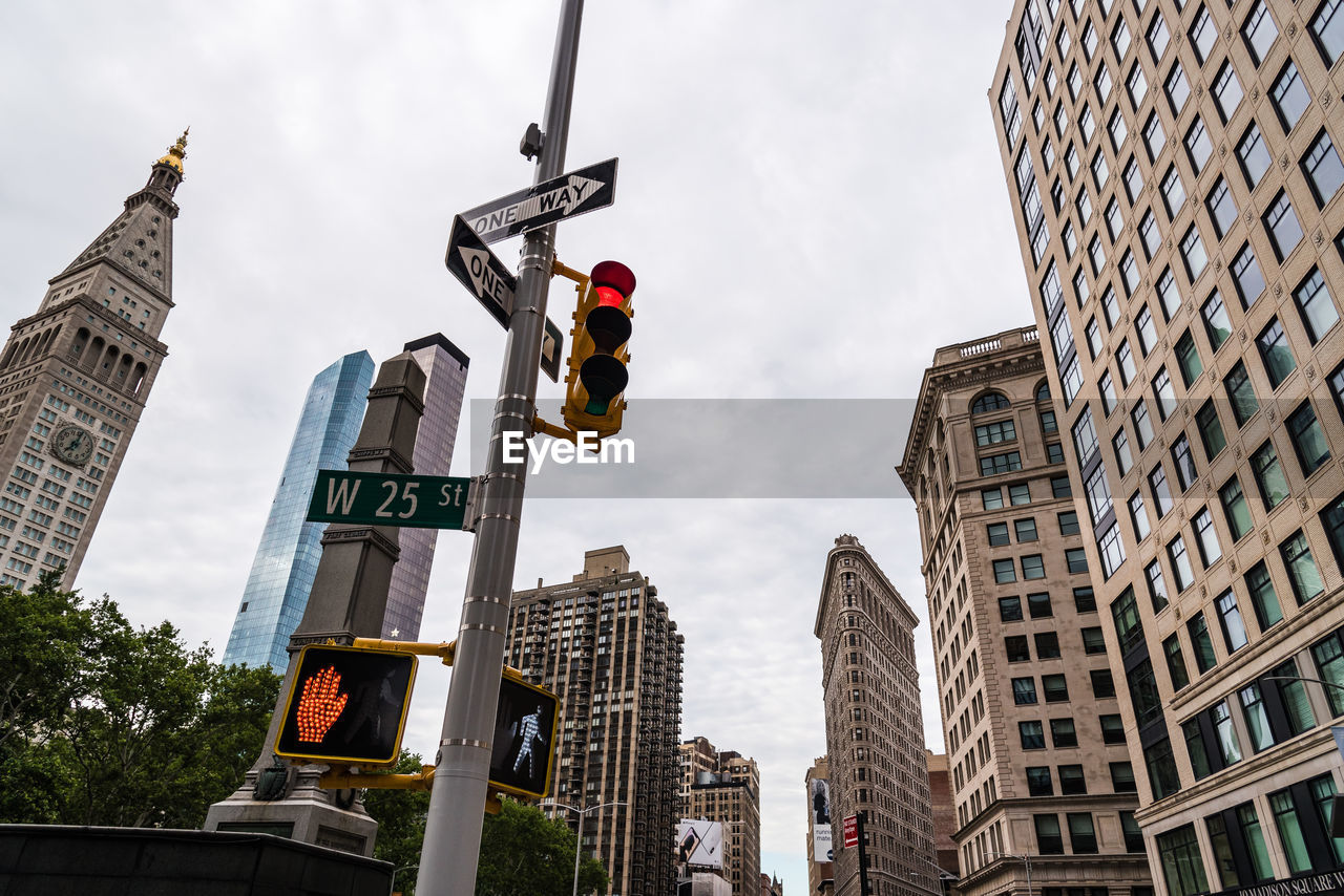Low angle view of directional signs and stoplight against buildings in city