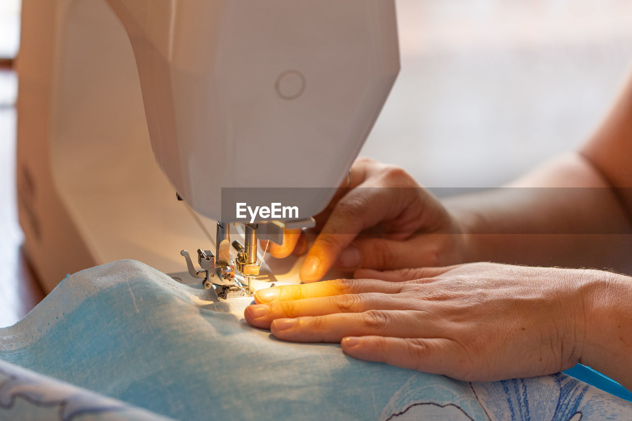 Sewing hands. female hands stitching fabric on a machine hobby at home. blurred