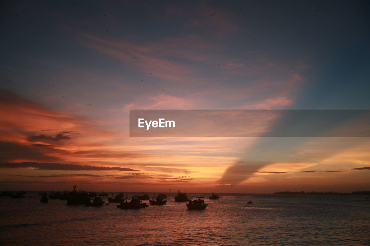 SILHOUETTE BOATS IN SEA AGAINST ORANGE SKY