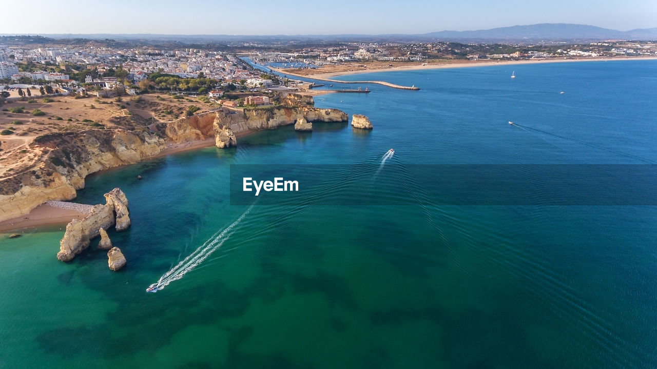 HIGH ANGLE VIEW OF SEA AND SHORE AGAINST BLUE SKY