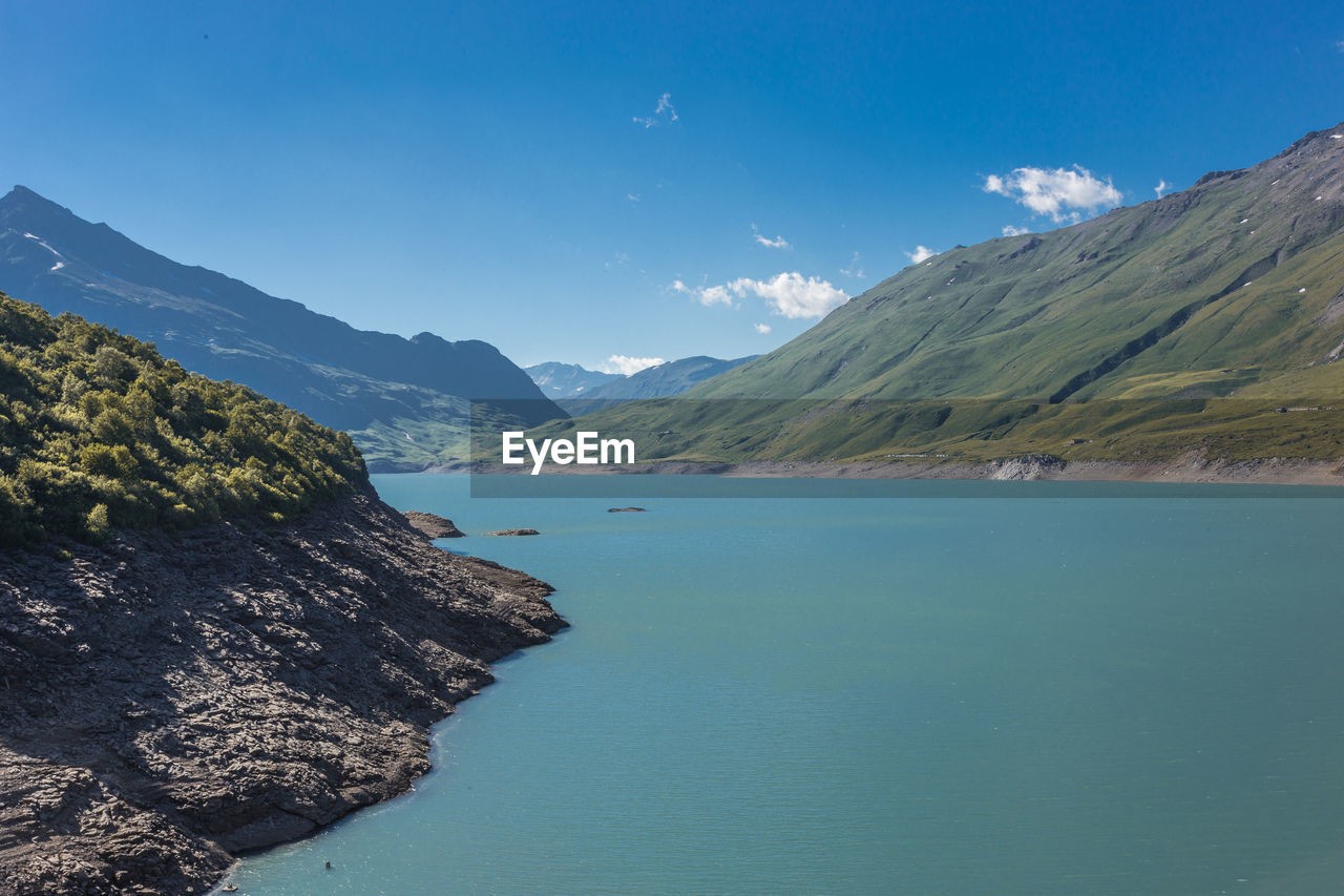 Scenic view of sea and mountains against blue sky