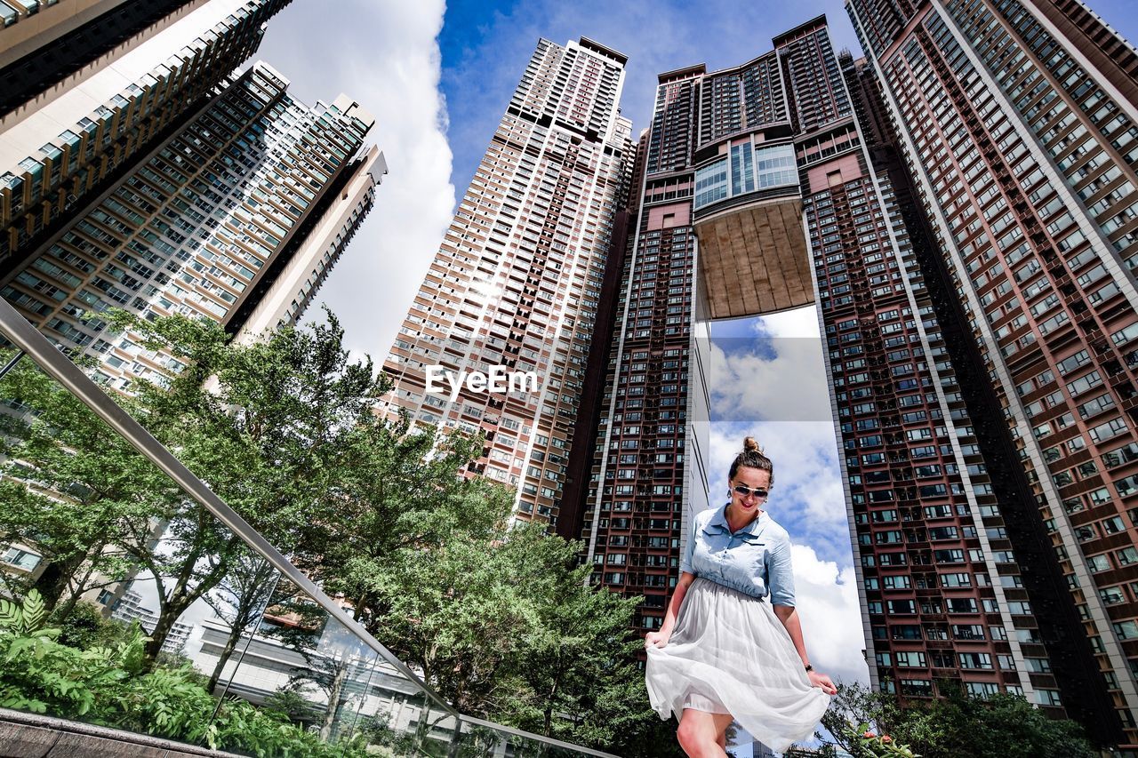 Low angle view of woman standing against buildings in city