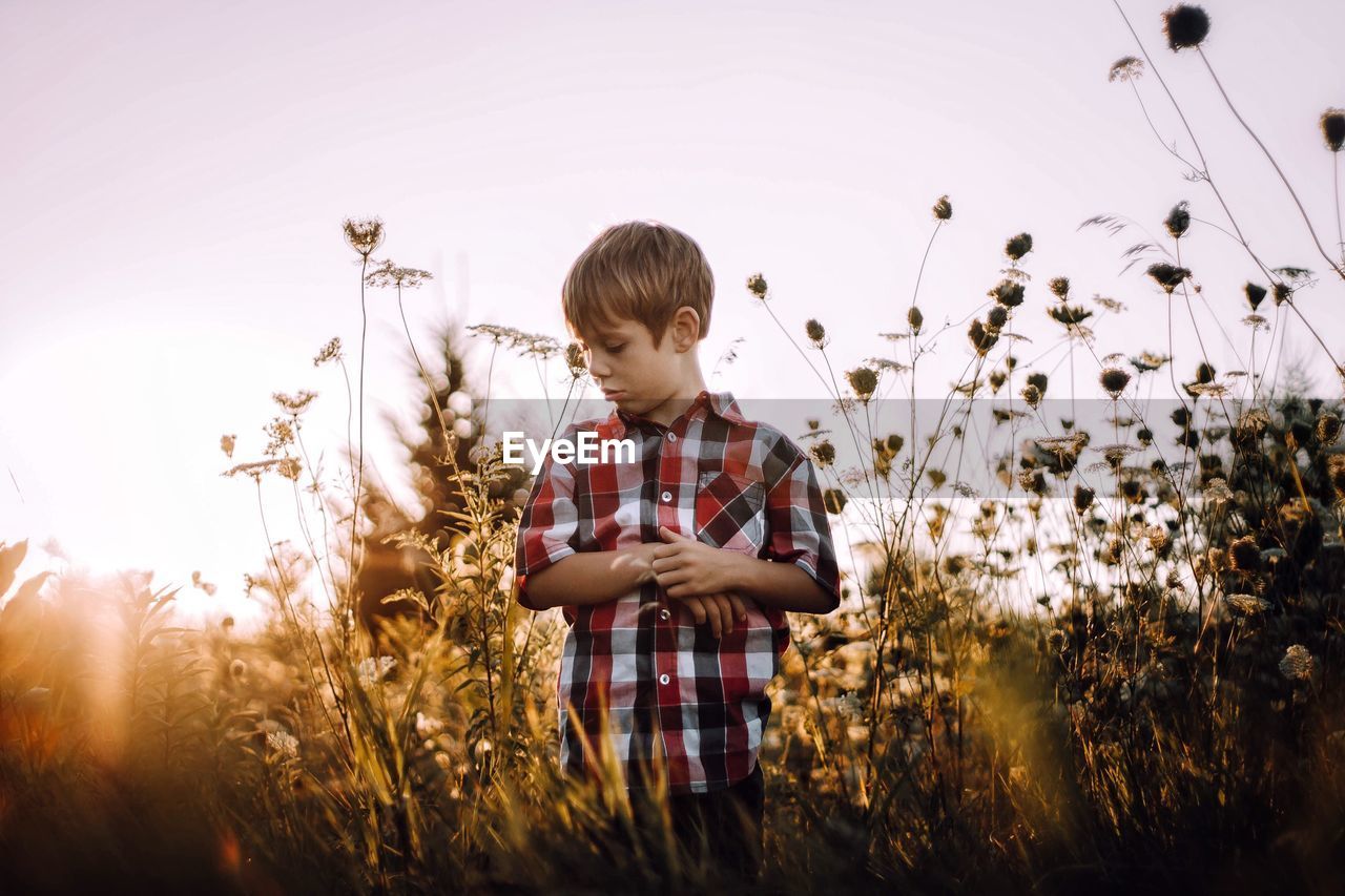 Boy standing on field against clear sky