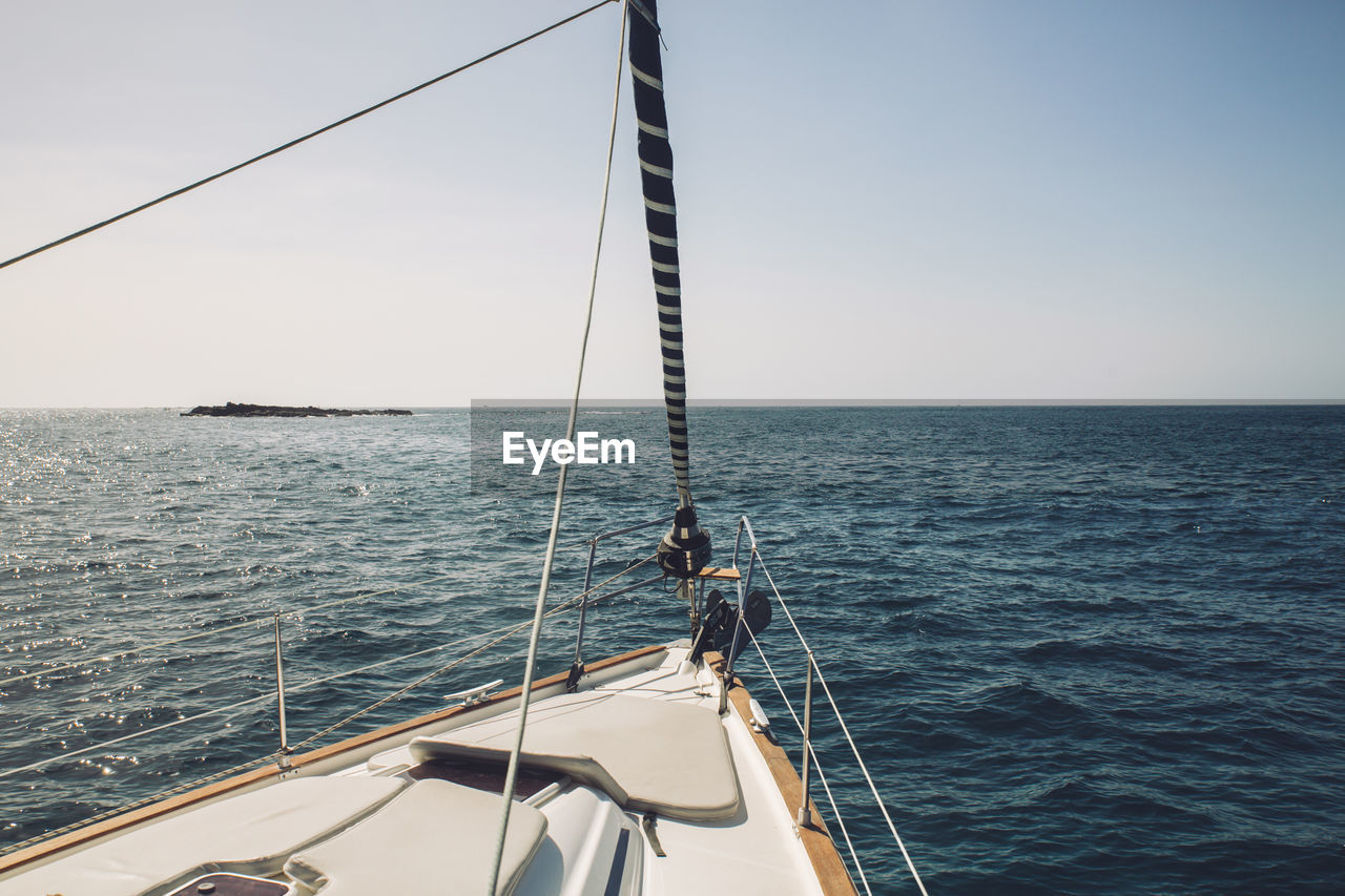 Sailboat sailing on sea against clear sky