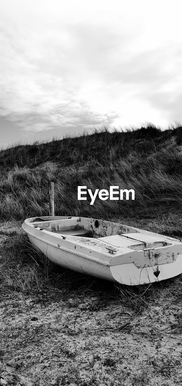 BOATS MOORED ON BEACH AGAINST SKY