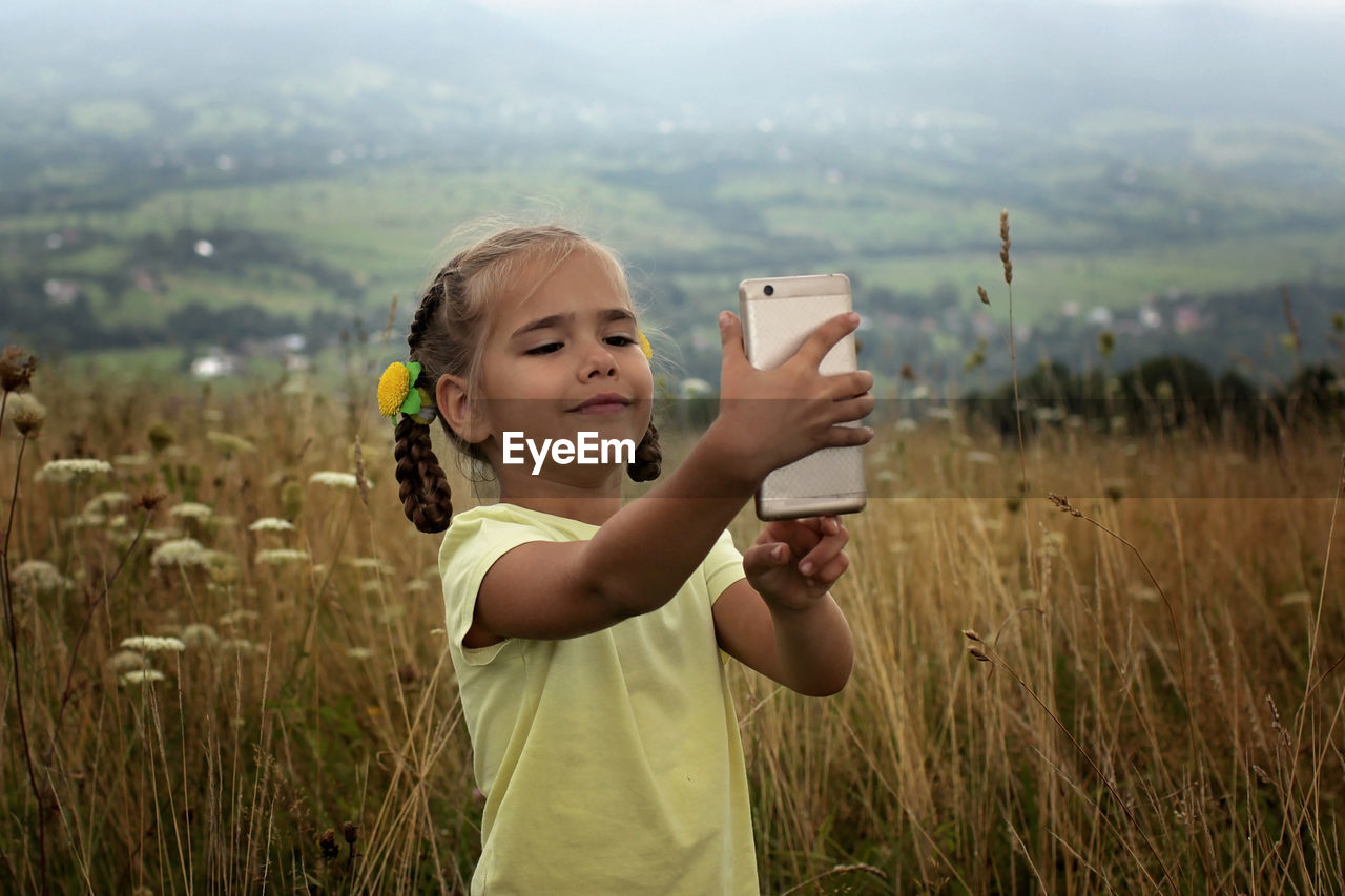 Cute 5-6 years old little girl sharing a photo on social media in internet in the mountains