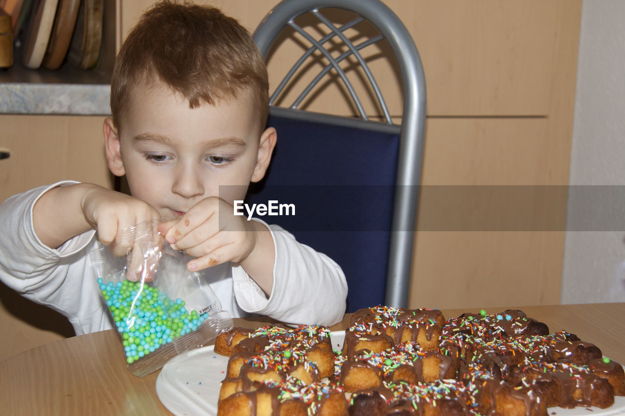 PORTRAIT OF CUTE BOY WITH FOOD ON TABLE