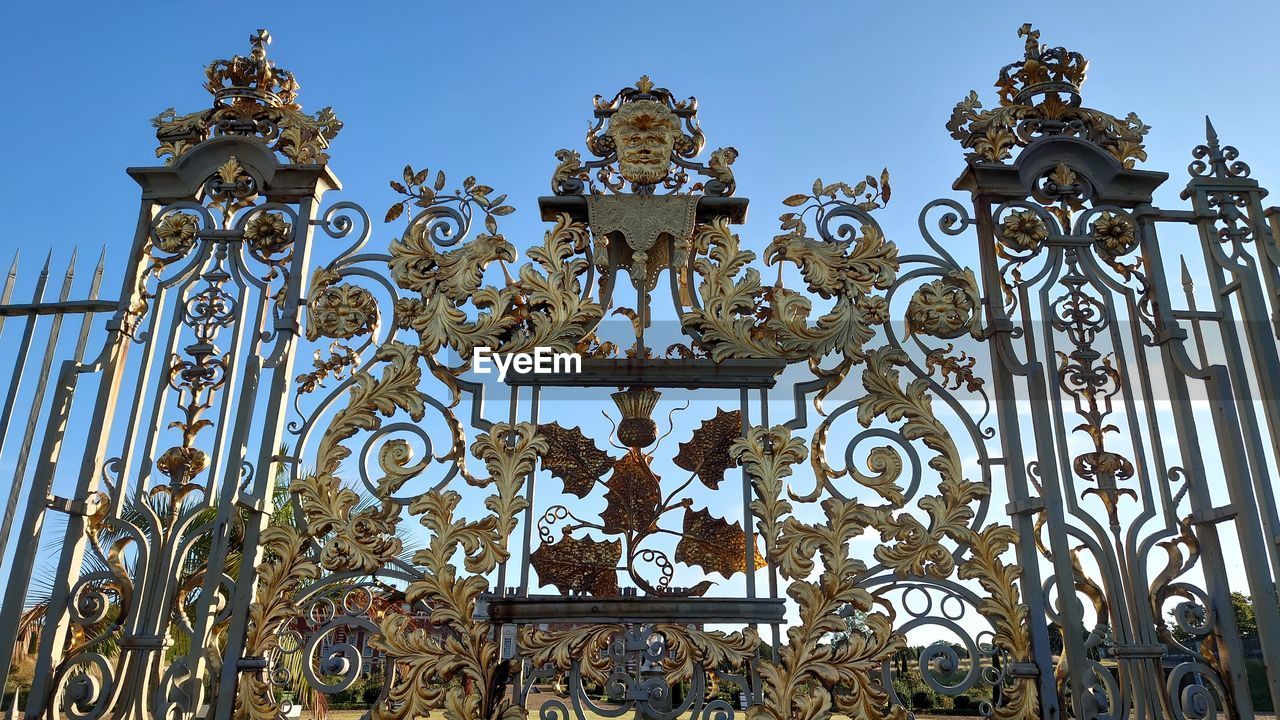 architecture, gate, sky, iron, no people, built structure, wrought iron, metal, ornate, travel destinations, clear sky, nature, history, the past, day, building exterior, building, travel, outdoors, religion, landmark, blue, low angle view, tourism, craft, sunny, pattern, belief, city