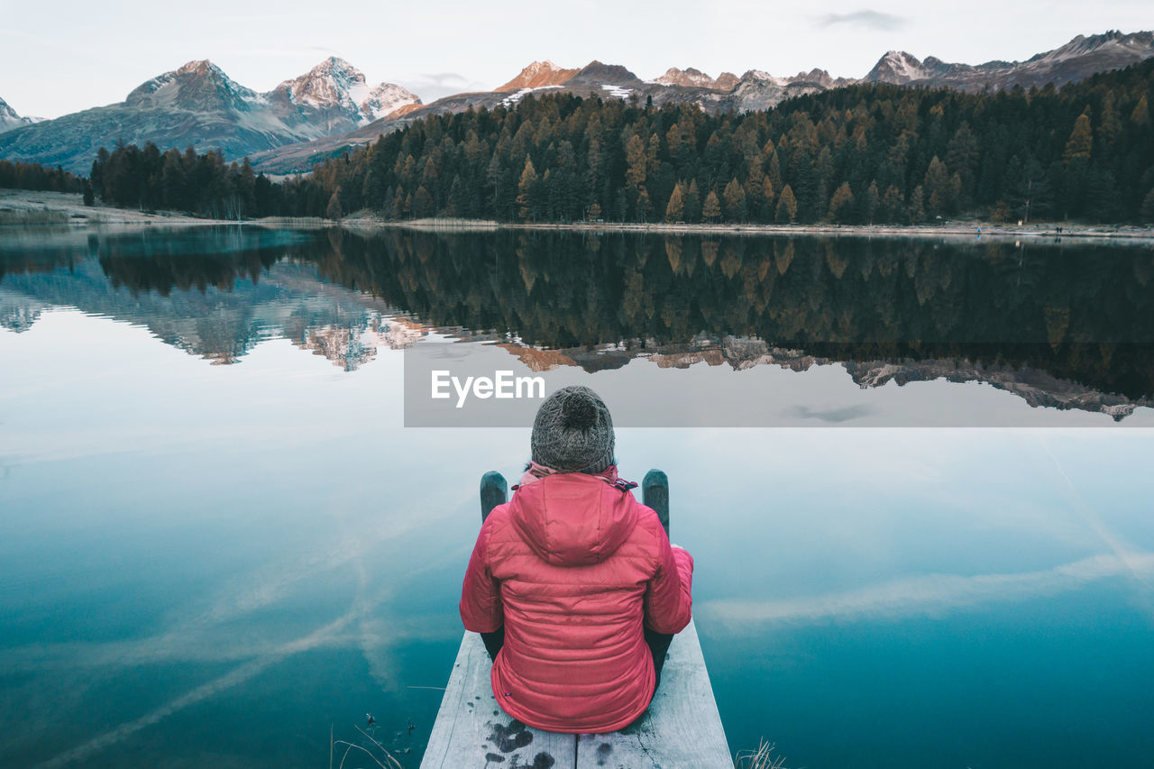 Rear view of woman looking at lake during winter