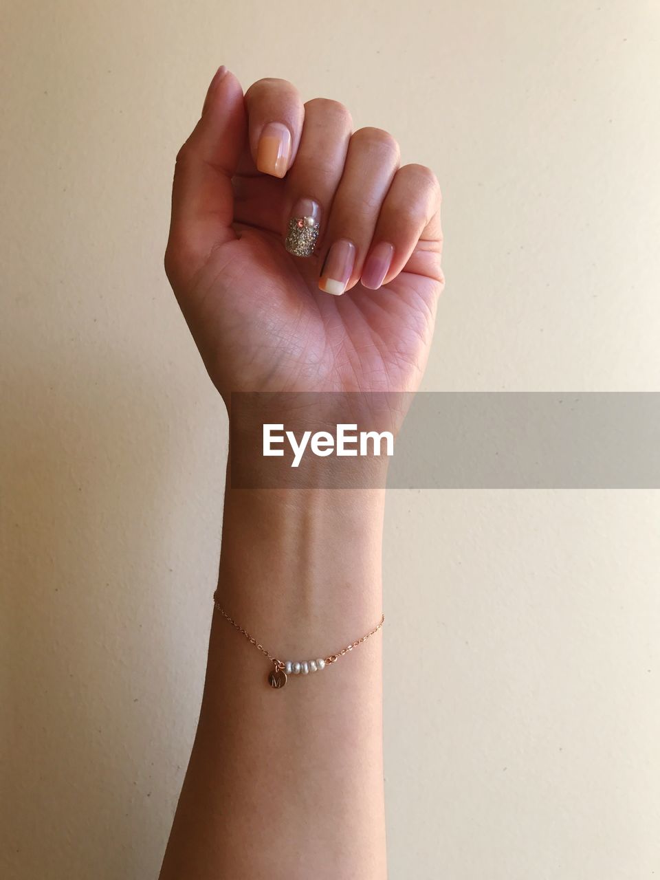 Cropped image of hand wearing bracelet against wall