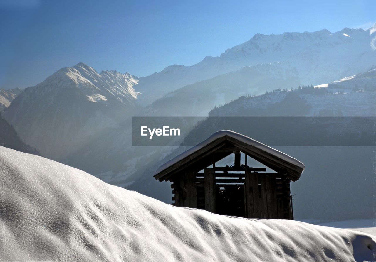 House on snowcapped mountains against sky