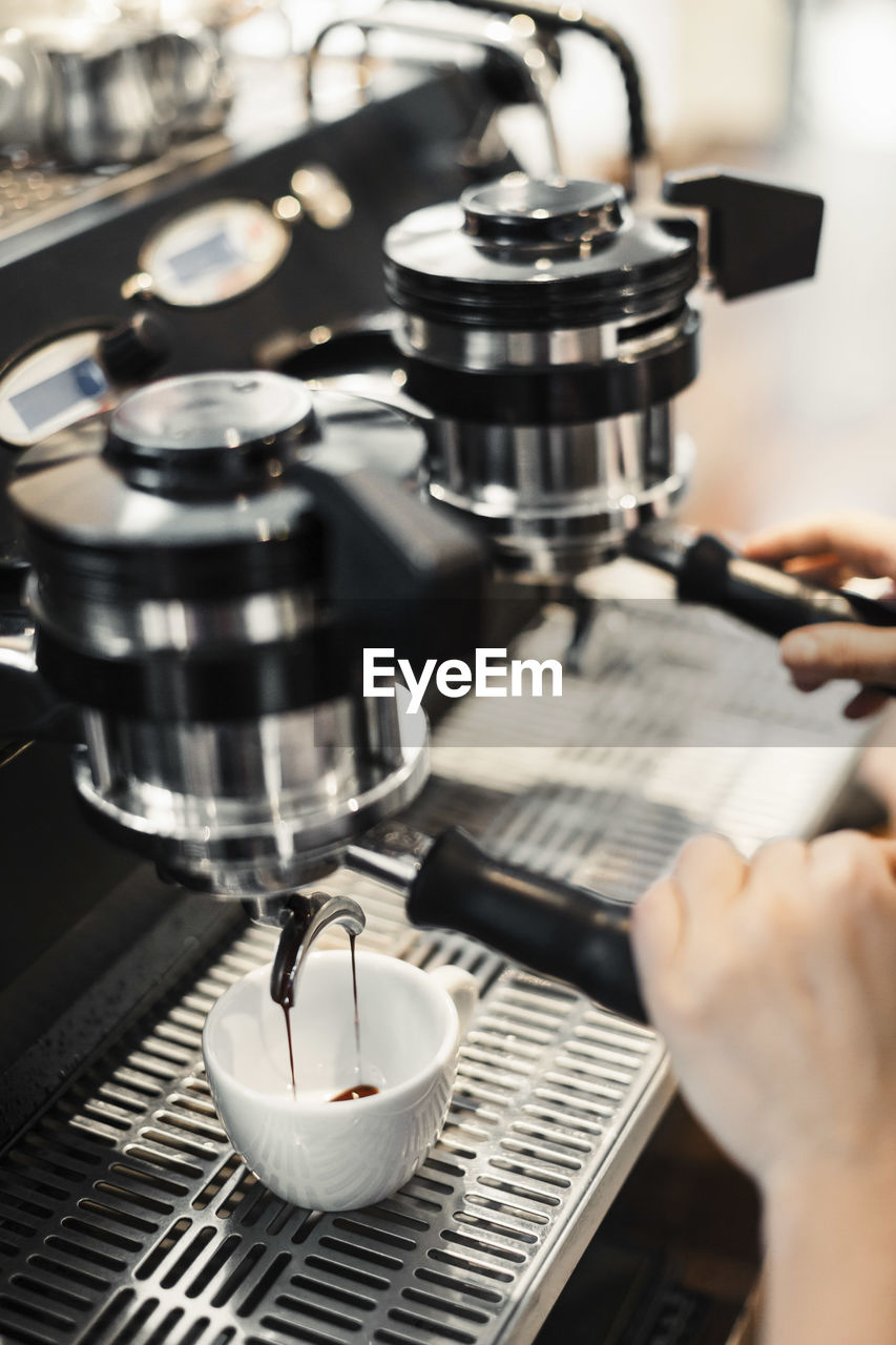 Cropped image of barista using coffee maker at cafe