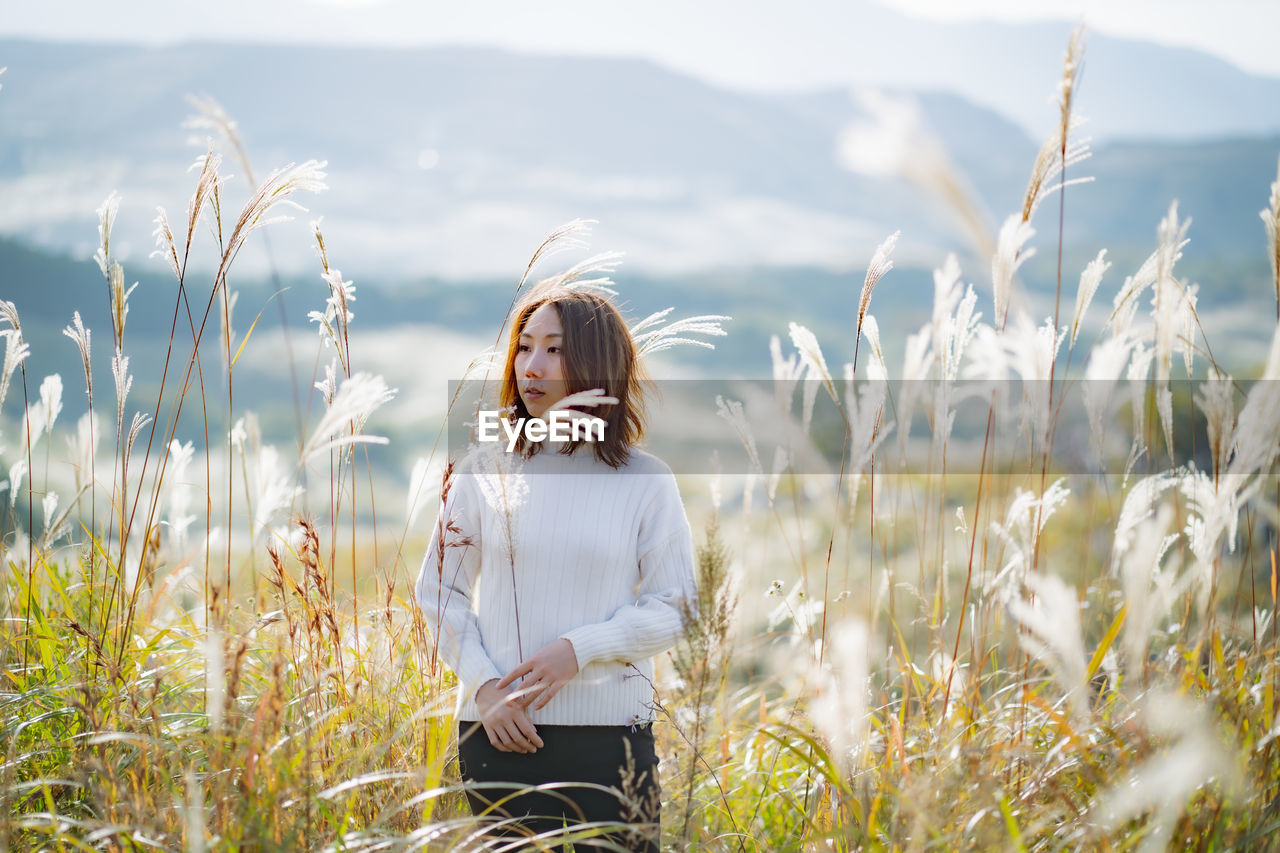 YOUNG WOMAN STANDING ON FIELD