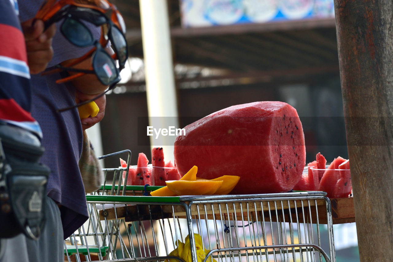 Midsection of people standing by sliced watermelons on table