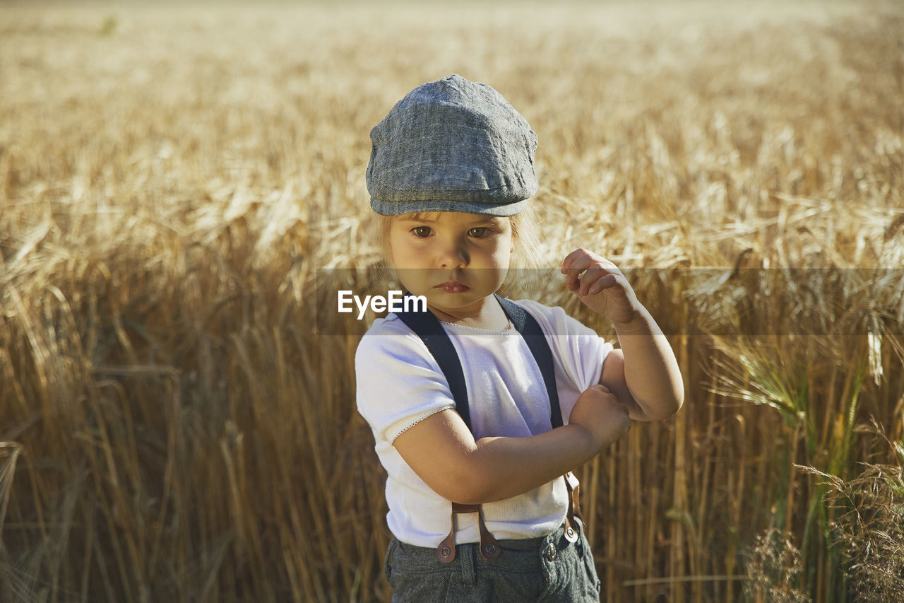 Adorable sad street child in a field at sunset