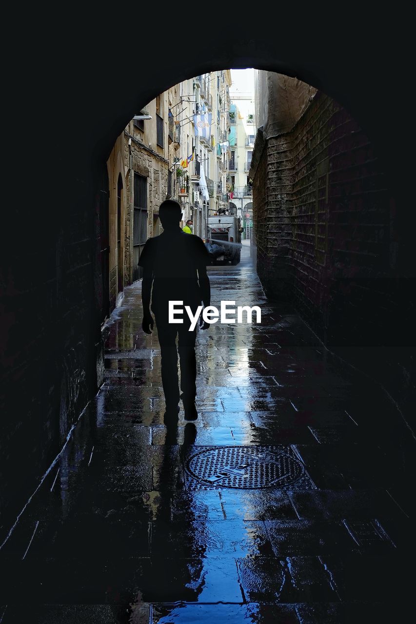 Rear view of person walking on wet street in city