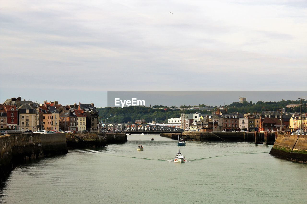 Scenic view of river by cityscape against sky