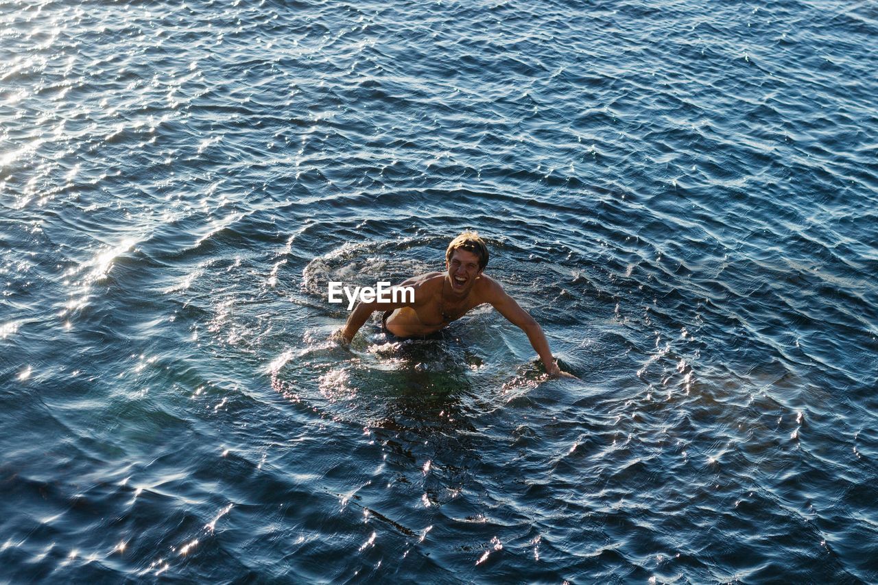 High angle view of shirtless man swimming in sea