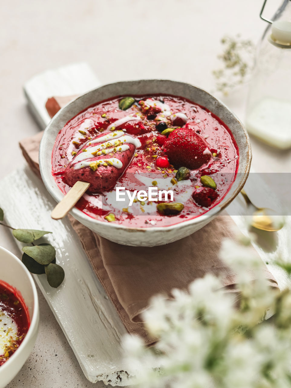 From above of tasty smoothie with fresh berries and ice candy with crushed pistachios and yogurt in bowl