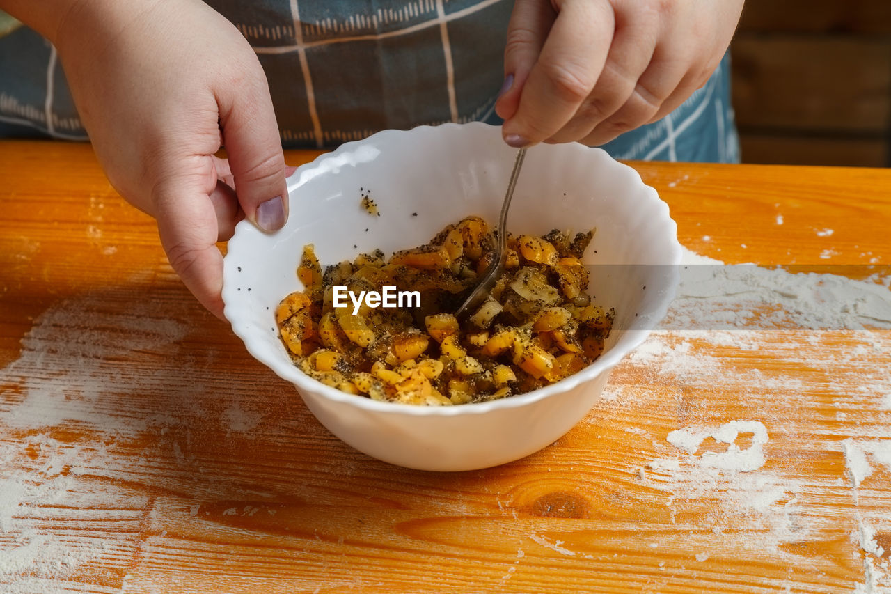 cropped hand of person preparing food in bowl on table