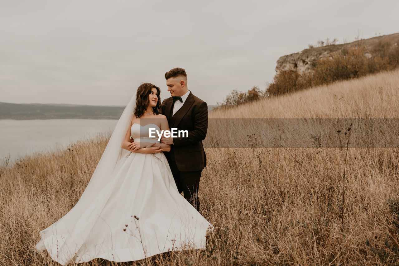 rear view of bride and groom standing on field