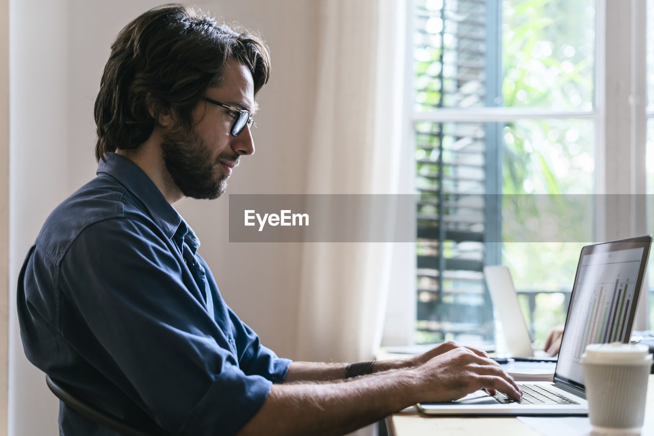 Businessman sitting in office, working at laptop