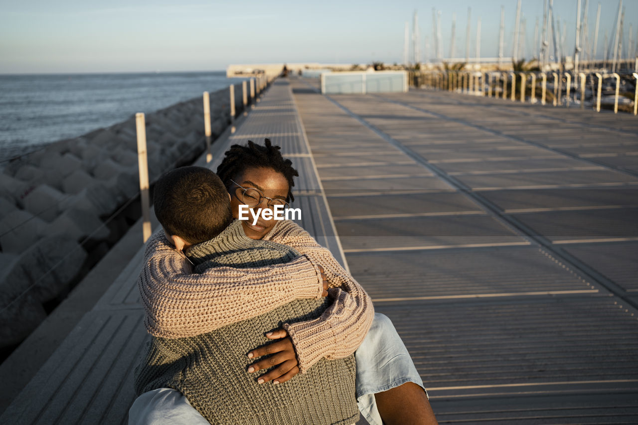 Female friends embracing each other while sitting on bench