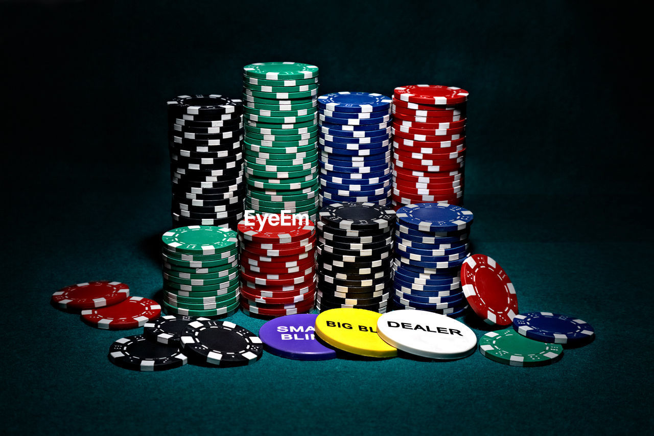 Stack of multi colored gambling chips on table against black background