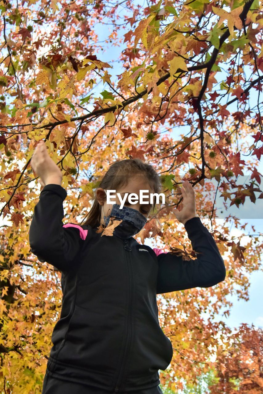 Low section of girl standing by tree