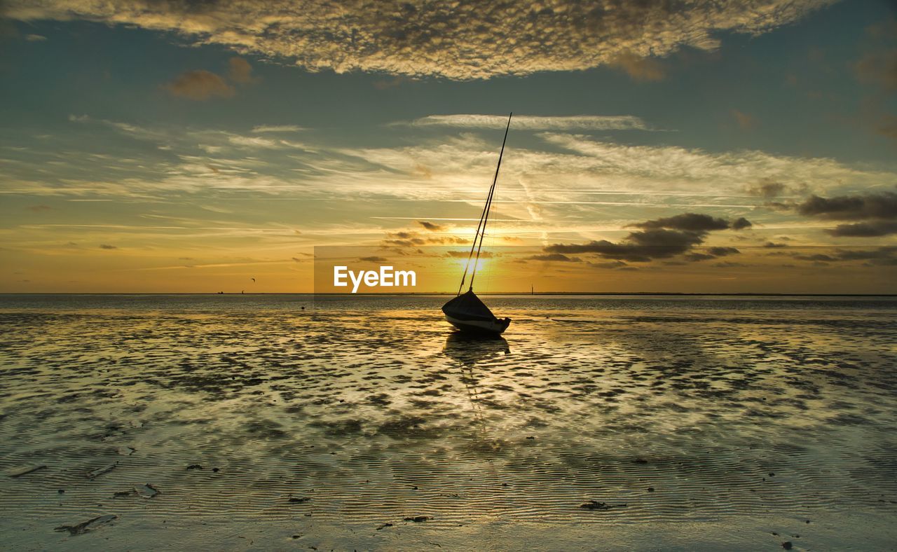 Silhouette sailboat on sea against sky during sunset