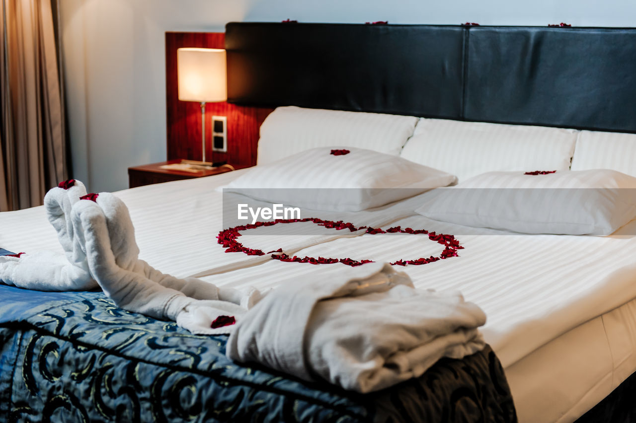 High angle view of red flower petals on bed in hotel room