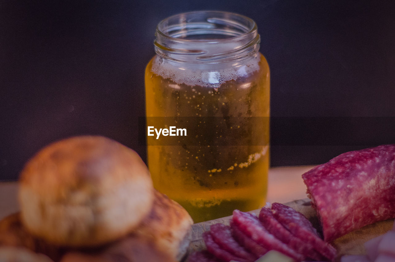 Close-up of beer in jar with bread and sliced salami on table