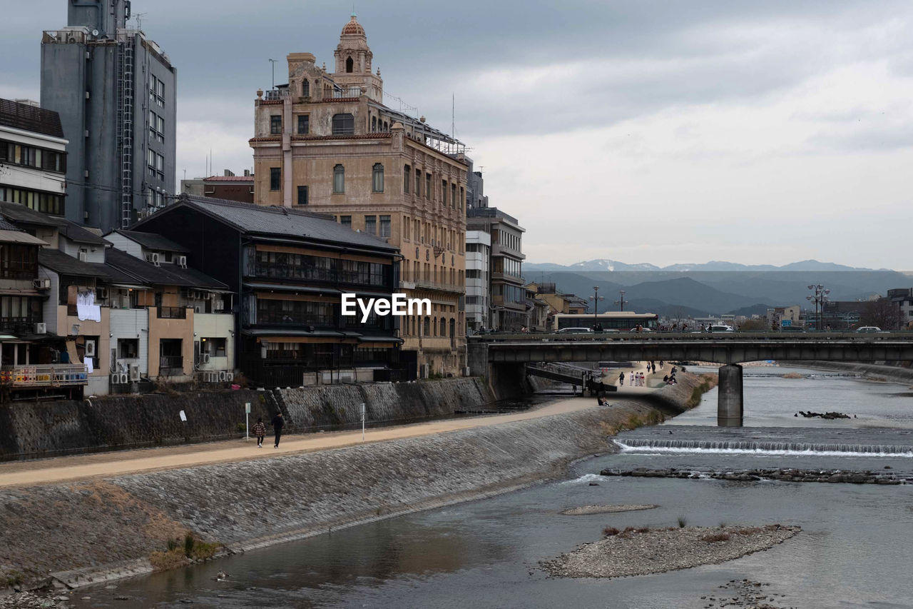 Bridge over kamo river by buildings in city against sky