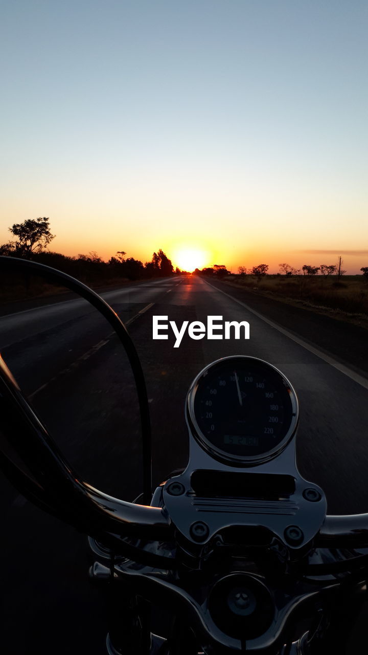 CAR ON ROAD IN CITY AGAINST SKY DURING SUNSET