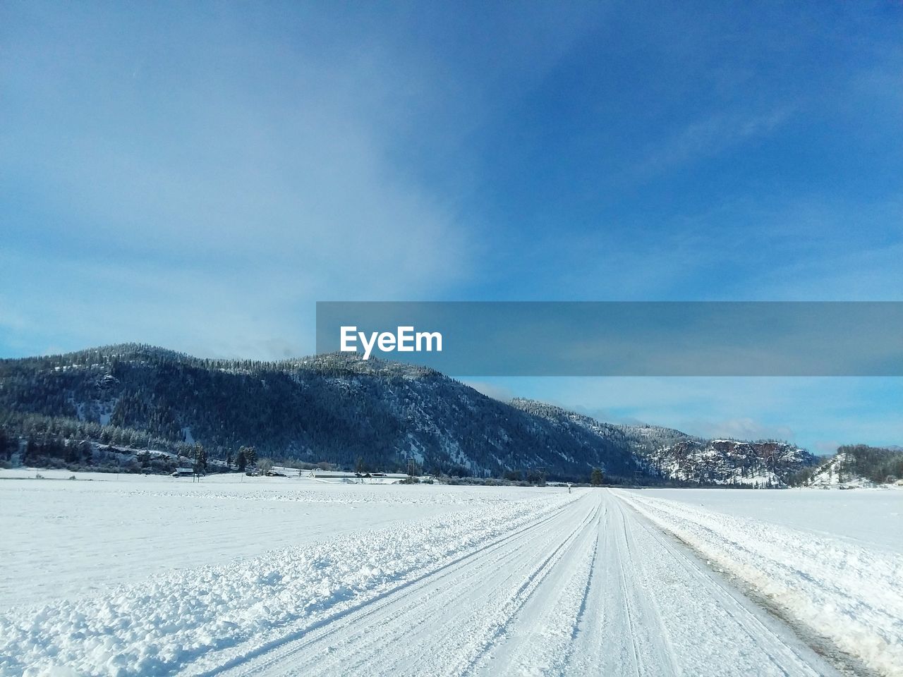 Snow covered road by mountain against sky