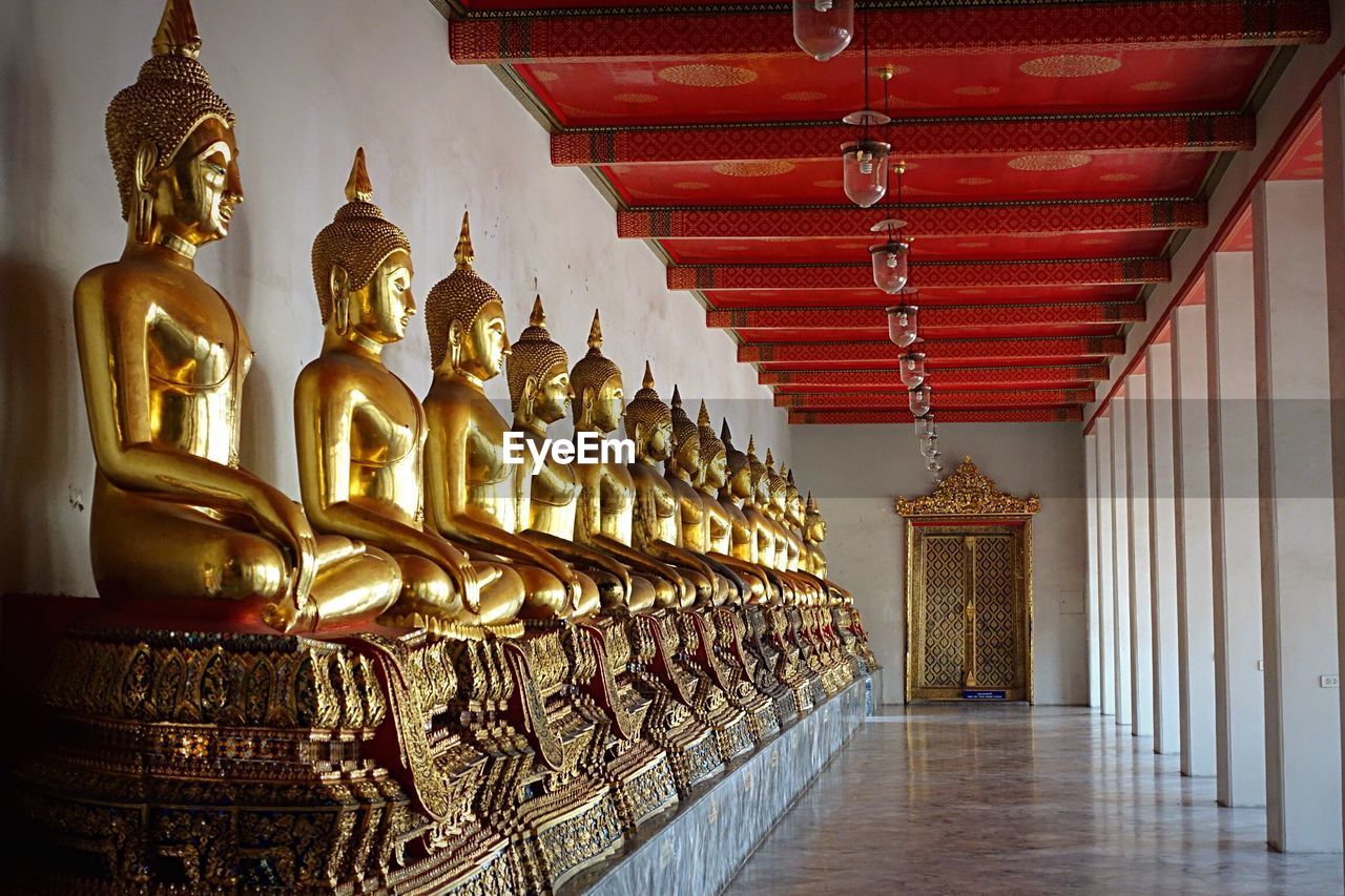 Gold buddha statues in row at wat pho corridor