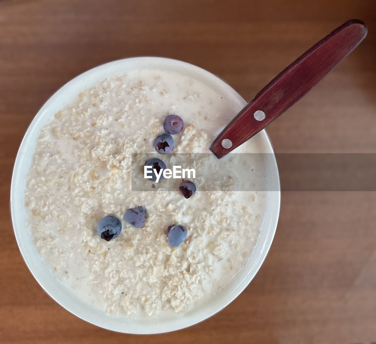 food and drink, food, blueberry, healthy eating, bowl, wellbeing, wood, spoon, breakfast, indoors, meal, kitchen utensil, eating utensil, table, produce, fruit, high angle view, no people, berry, freshness, dairy, close-up, dish, directly above, still life, cereal