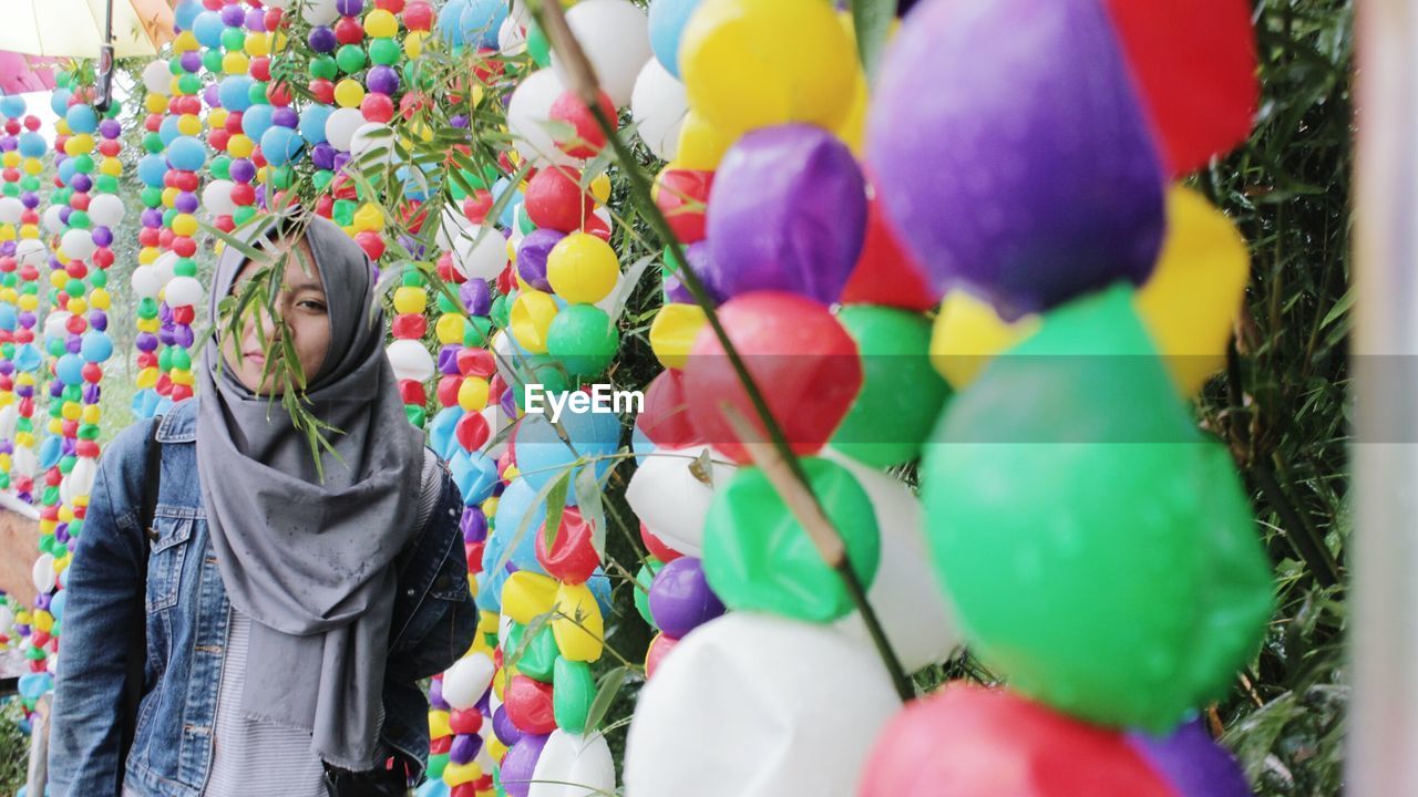 Portrait of woman standing by multi colored decorations