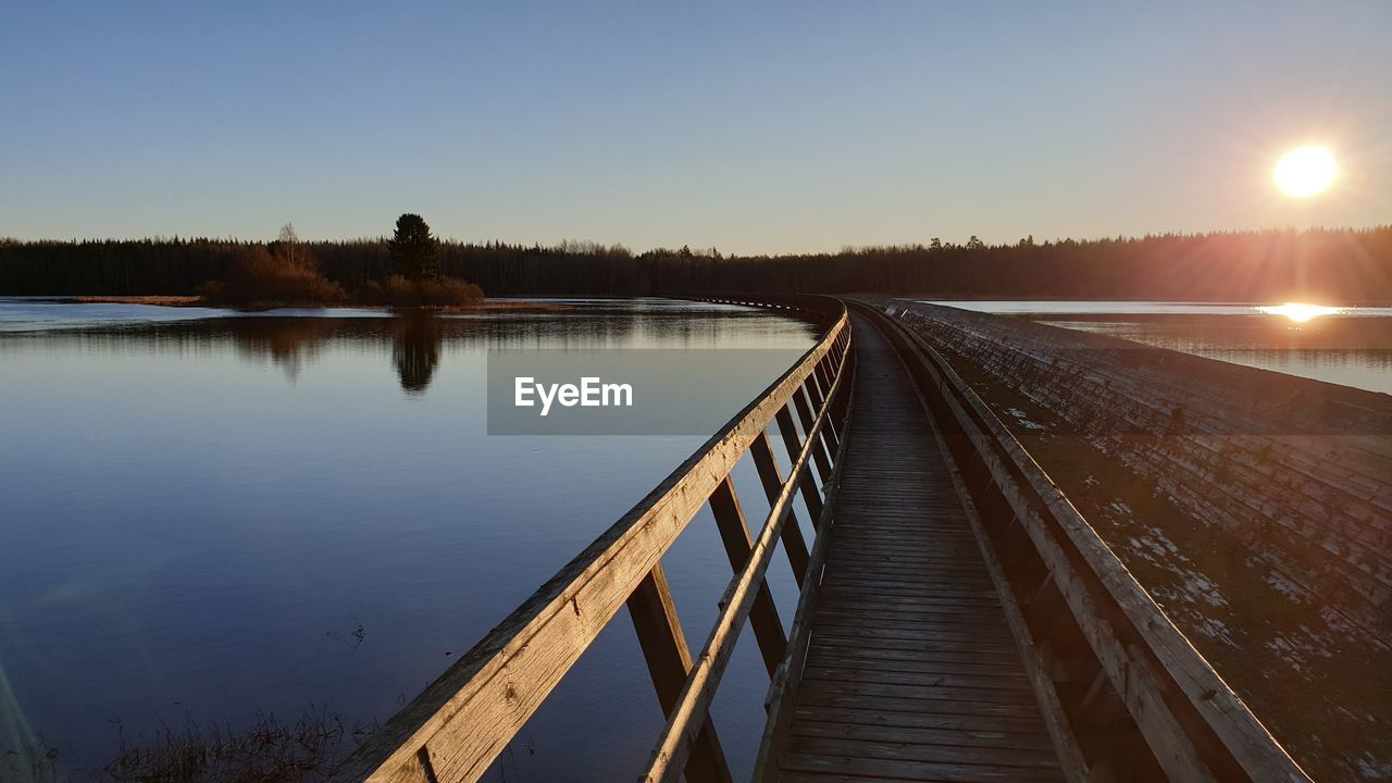 PIER OVER LAKE AGAINST CLEAR SKY DURING SUNSET