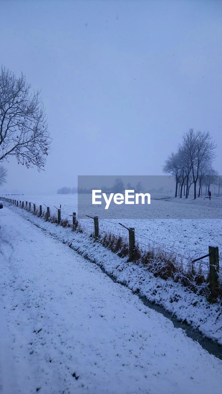 SCENIC VIEW OF FROZEN FIELD AGAINST CLEAR SKY