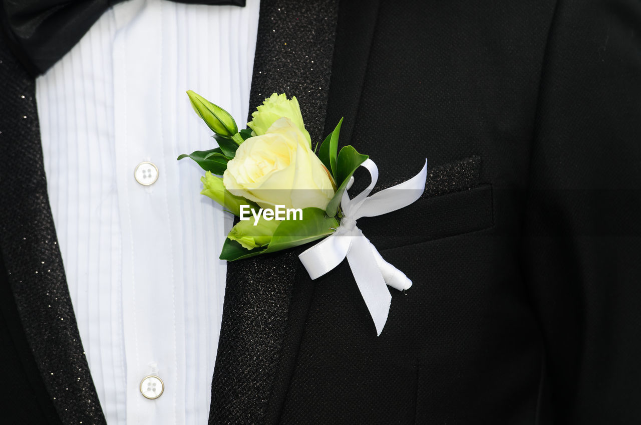 Midsection of bridegroom wearing suit with yellow rose in pocket